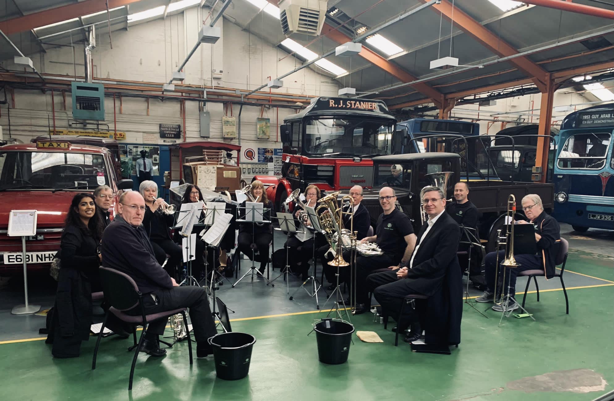 Great Barr Brass seated in front of buses at Aldridge Transport Museum.