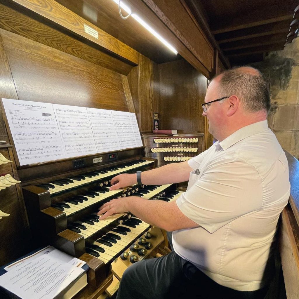 Andrew Clayton sat at the console of the church organ, playing it.