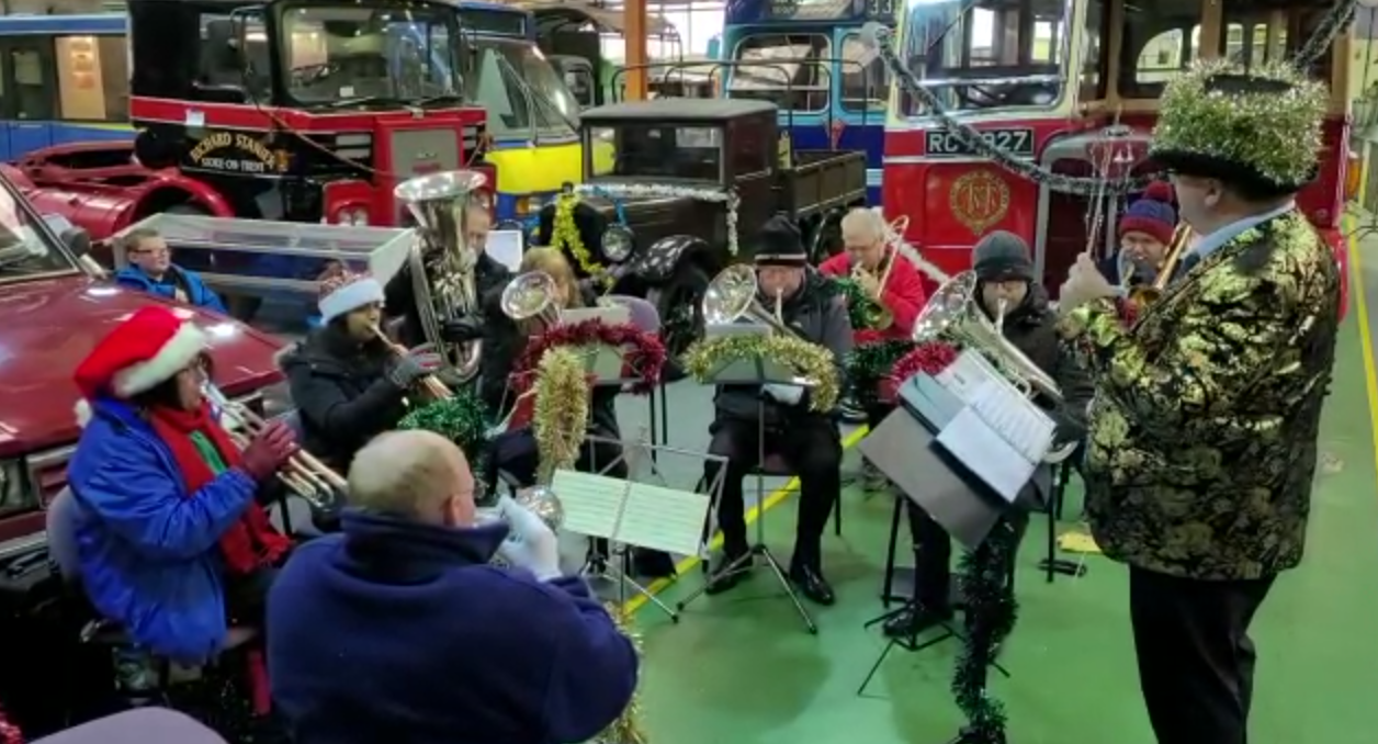 Great Barr Brass conducted by Andrew Clayton in Christmas dress, in a bus museum